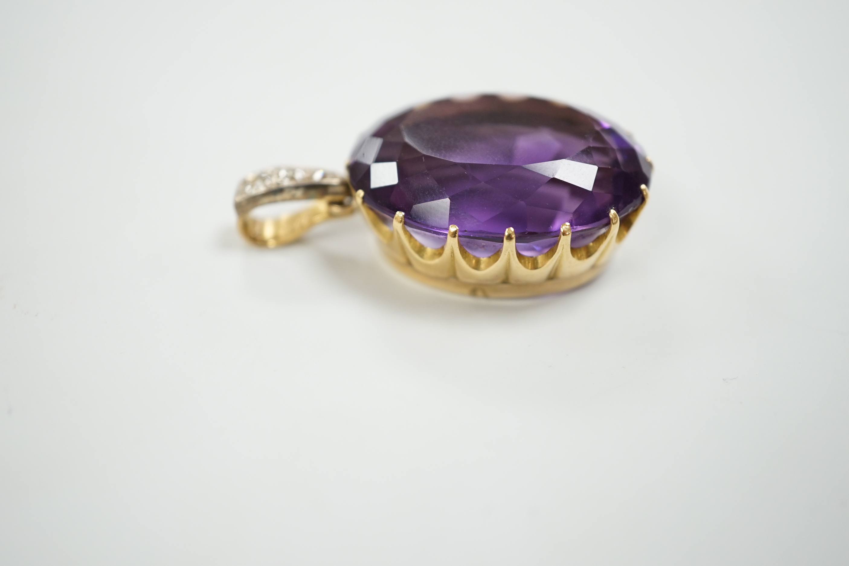 An Edwardian yellow metal, oval cut amethyst and three stone diamond set drop pendant, overall 4cm, gross weight 16.7 grams.